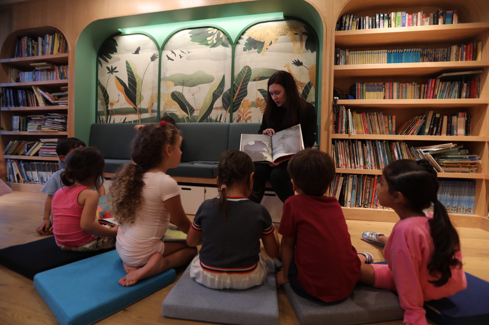 A Page Zero facilitator reading a picture book to a circle of young children